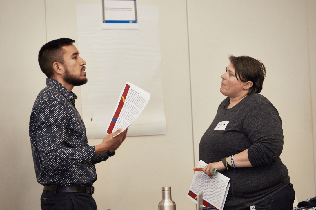 Octavio Casas, Transformation Coach at NCS, discusses with an educator at an NCS professional learning space.